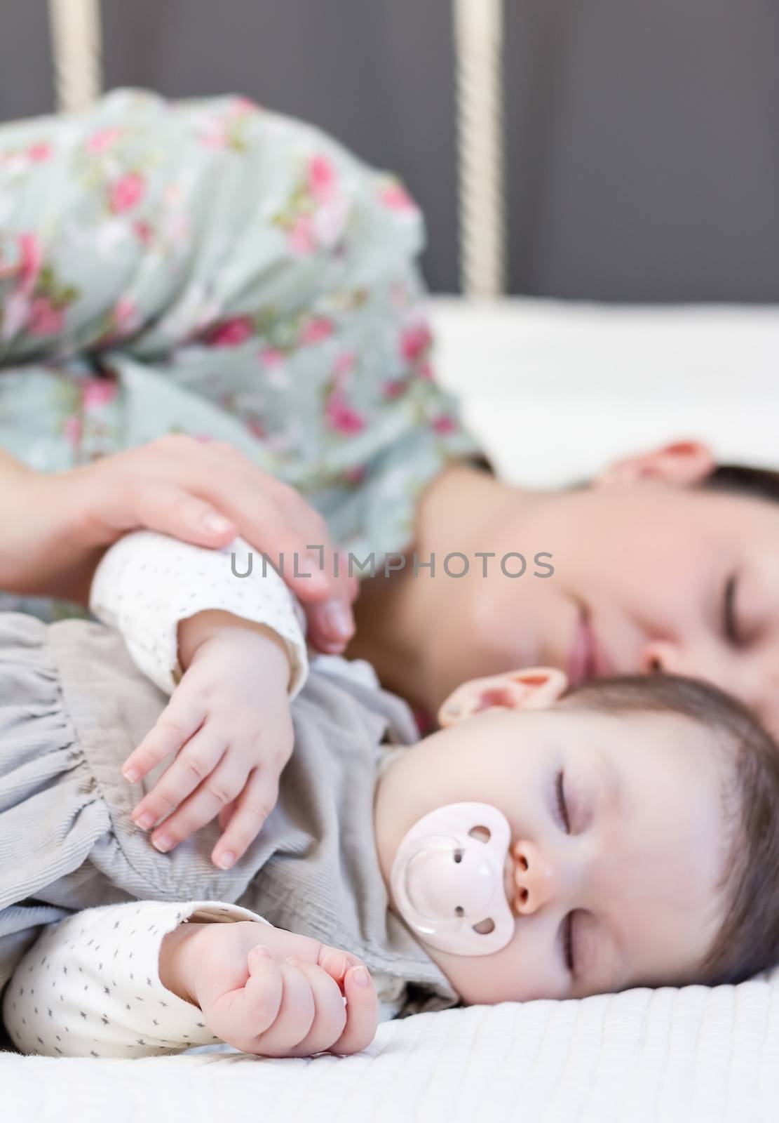 Young mother and her cute baby girl sleeping together in the bed