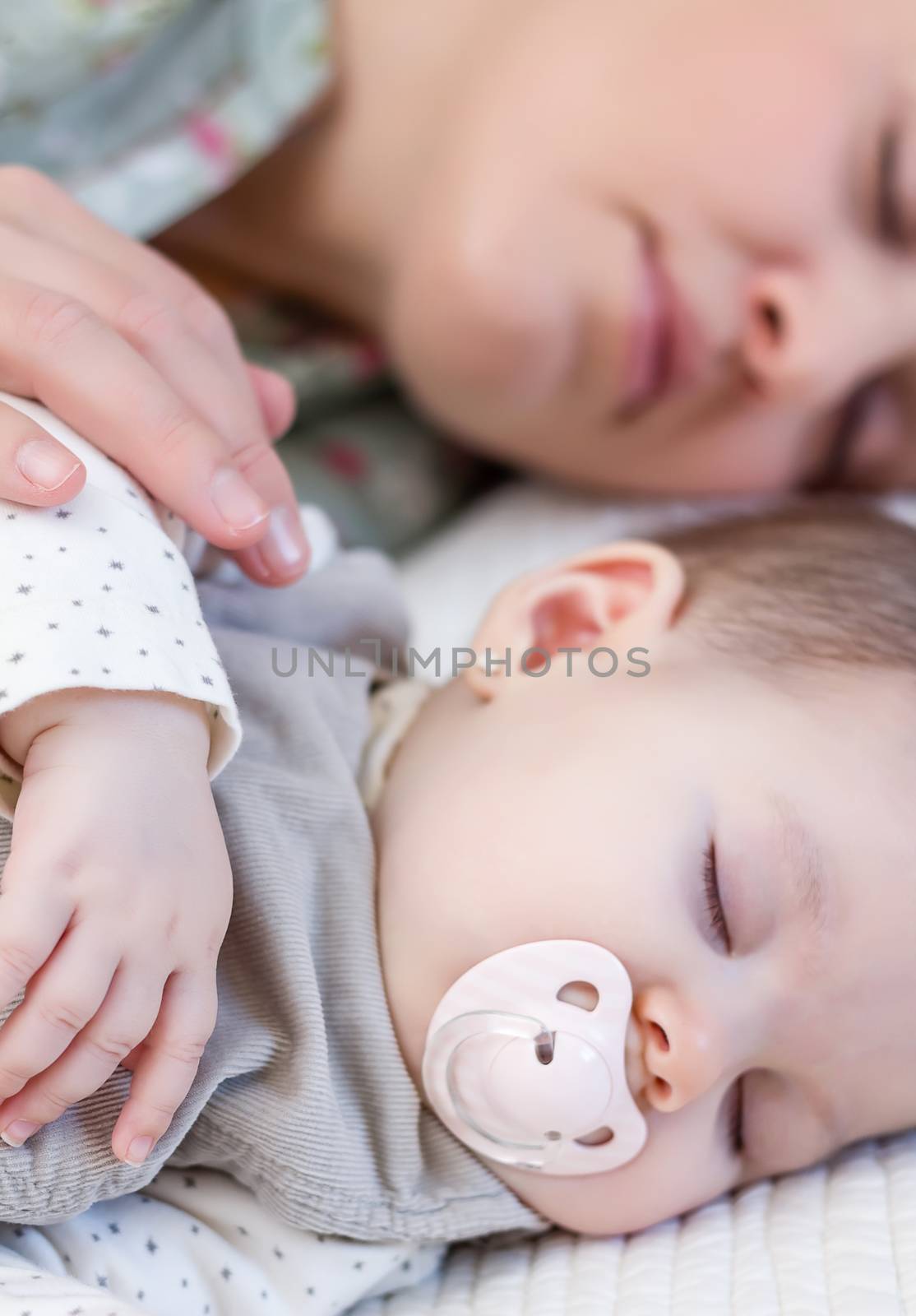 Young mother and her cute baby girl sleeping together in the bed