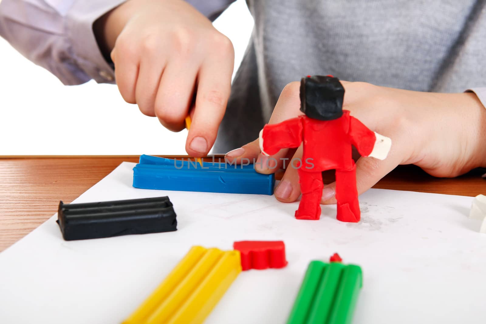 Kid playing with Plasticine at the School Desk Closeup