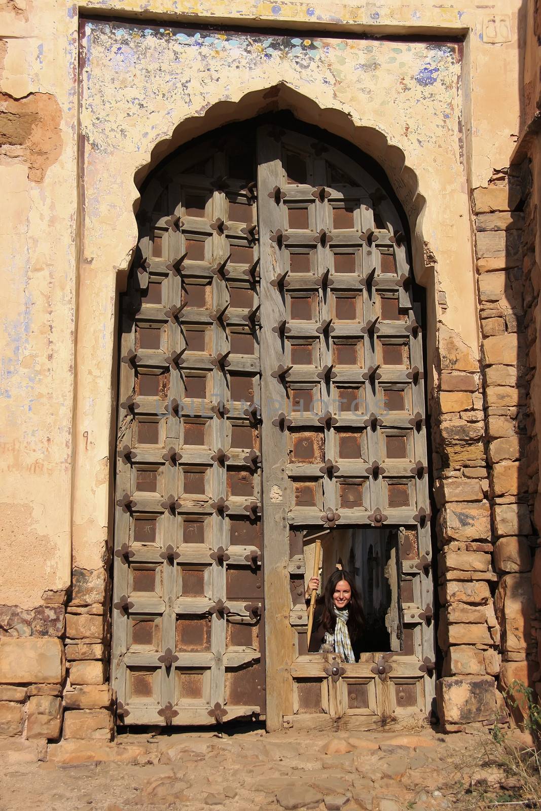 Young woman looking through big gate of Taragarh Fort, Bundi,  Rajasthan, India