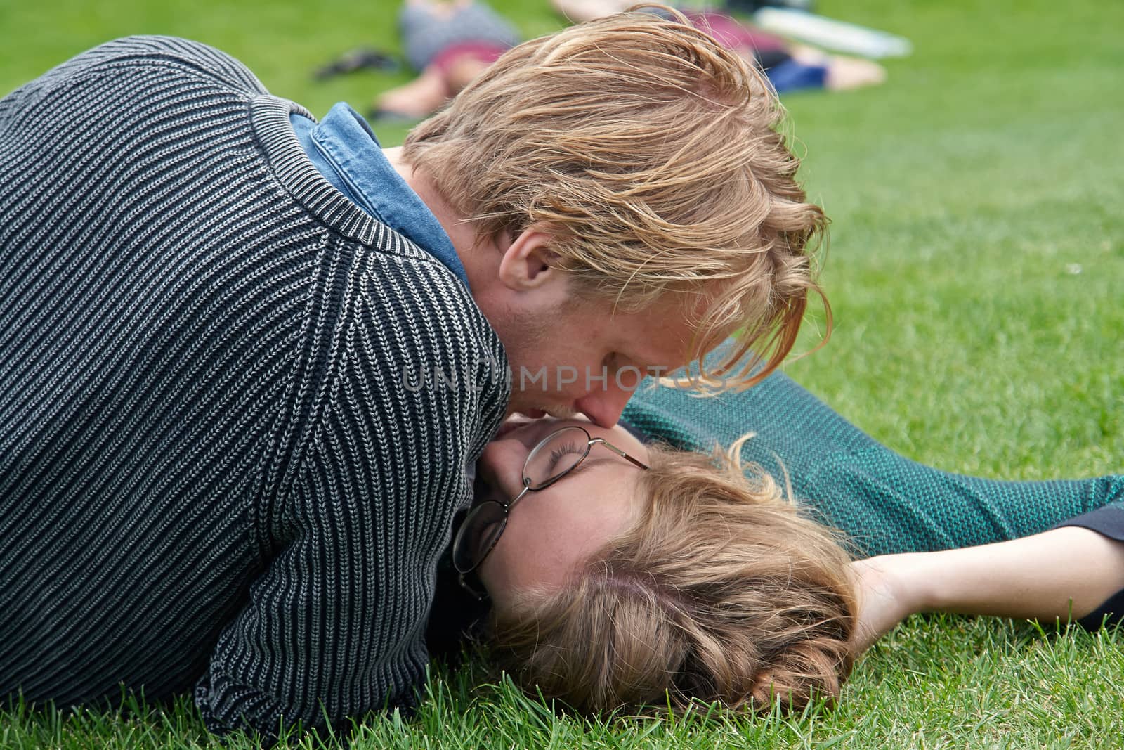 Young couple deeply in love outdoors on the grass in a park                              
