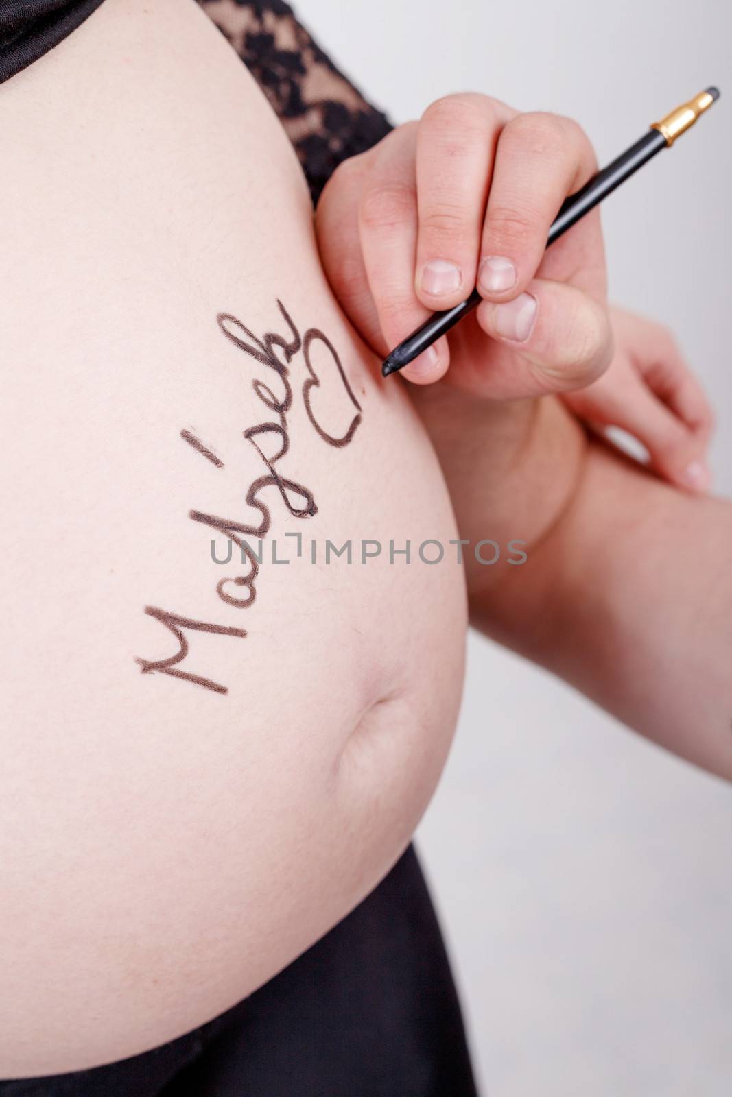 loving happy couple, pregnant woman with her husband, husband writing name of baby to her tummy