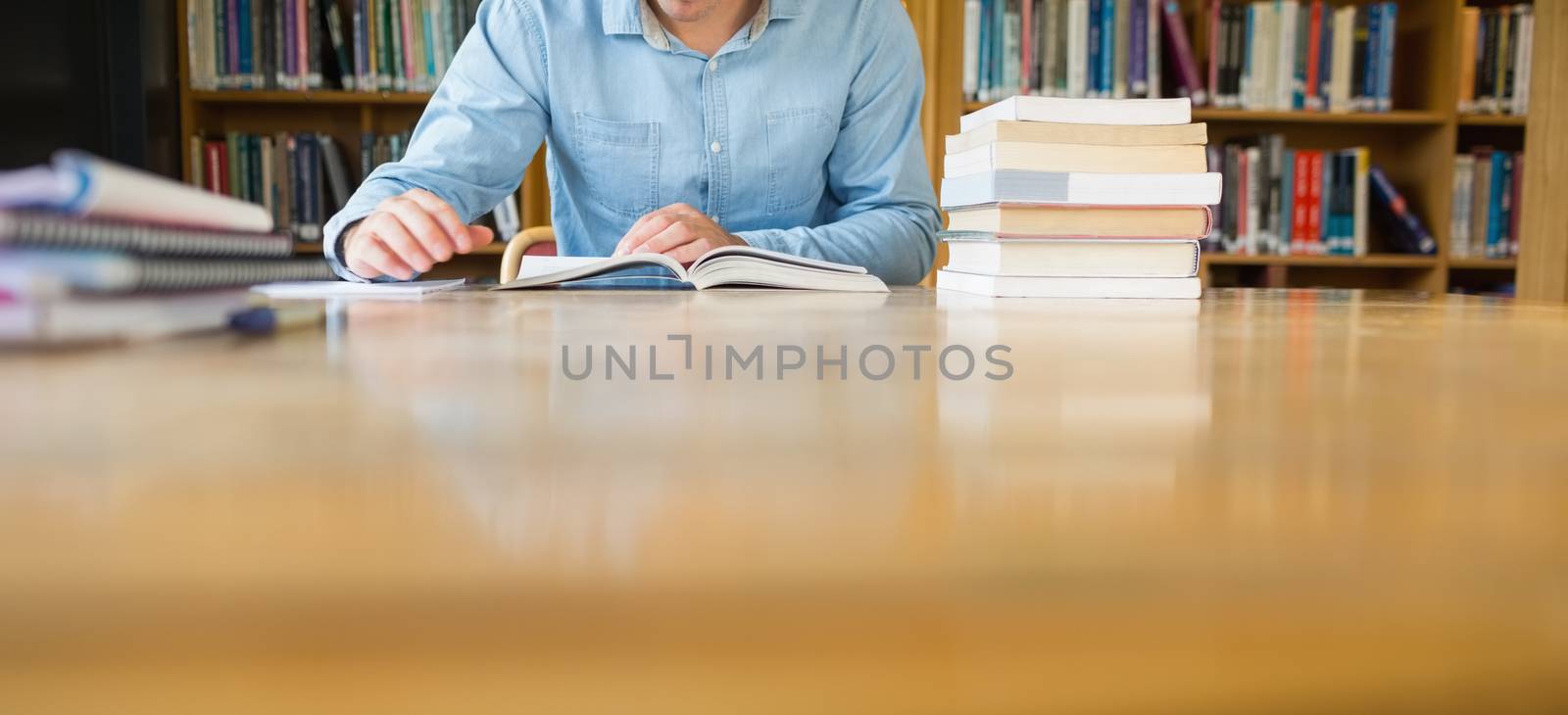 Mid section of a student studying at library desk by Wavebreakmedia