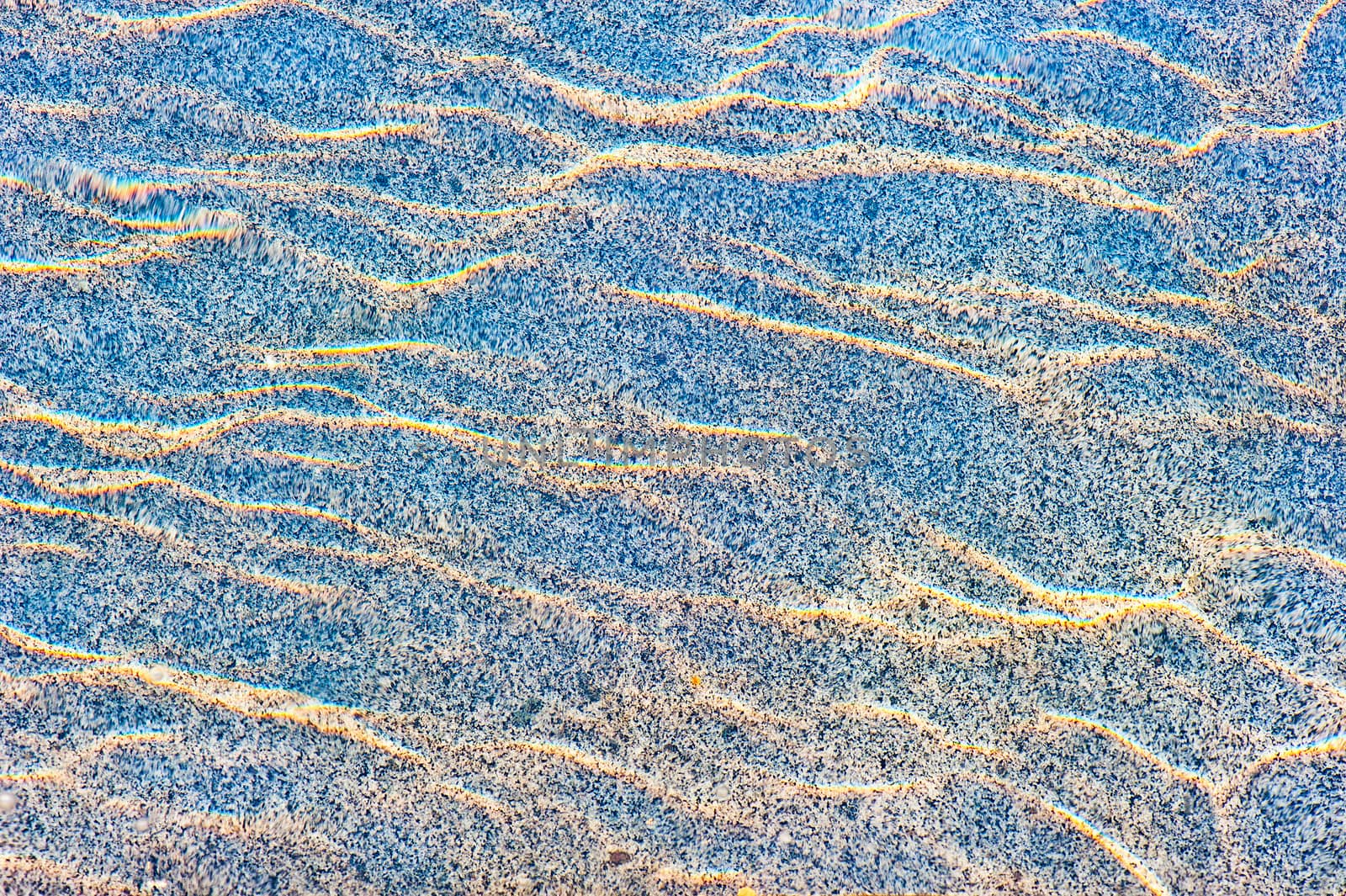 Sun reflections on a marble slab in pool water from above.