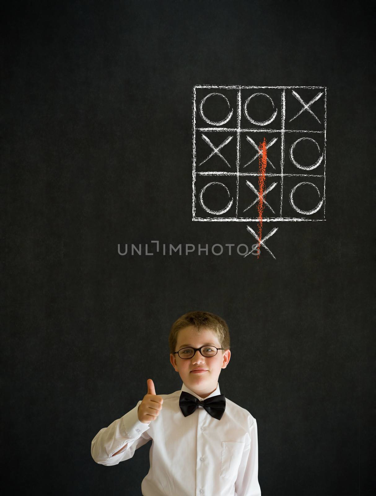 Thumbs up boy dressed up as business man with thinking out of the box tic tac toe concept on blackboard background