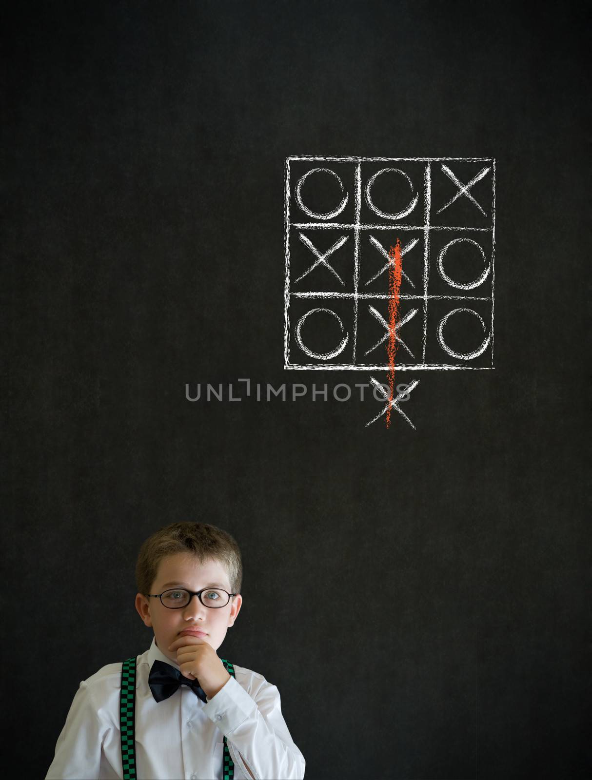 Thinking boy dressed up as business man with thinking out of the box tic tac toe concept on blackboard background