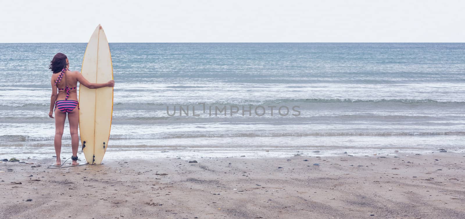 Calm woman in bikini with surfboard on beach by Wavebreakmedia