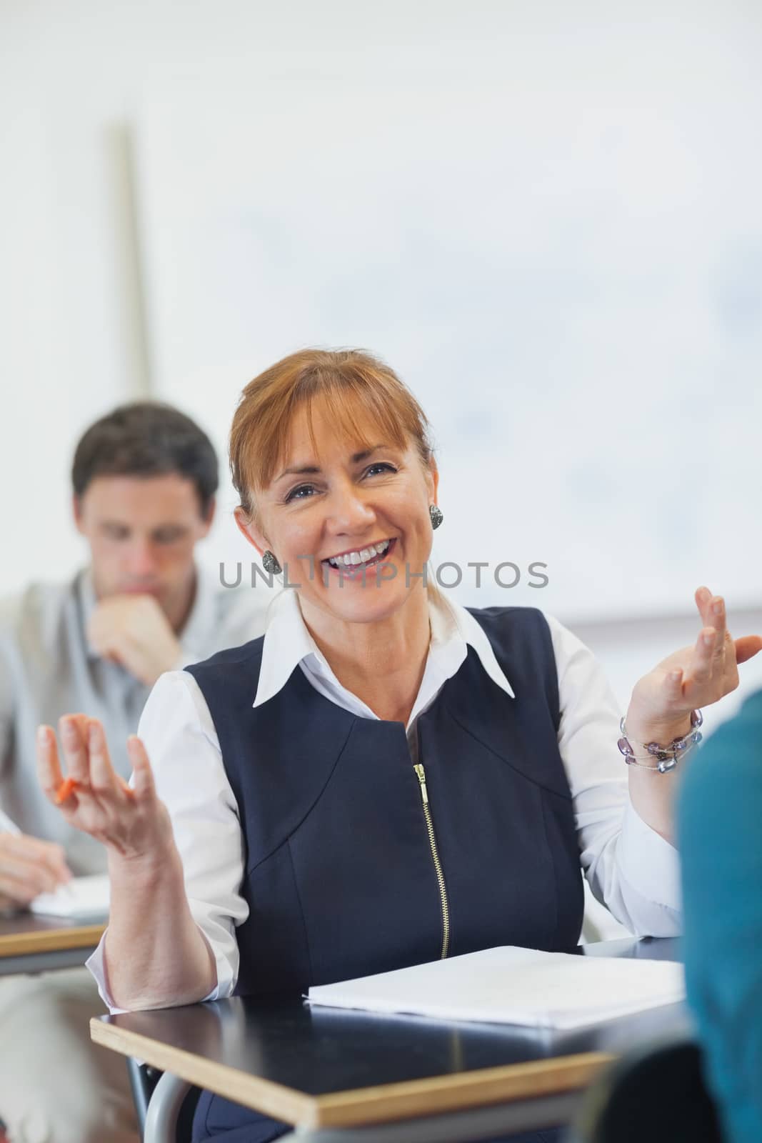 Amused female mature woman sitting in classroom making a gesture