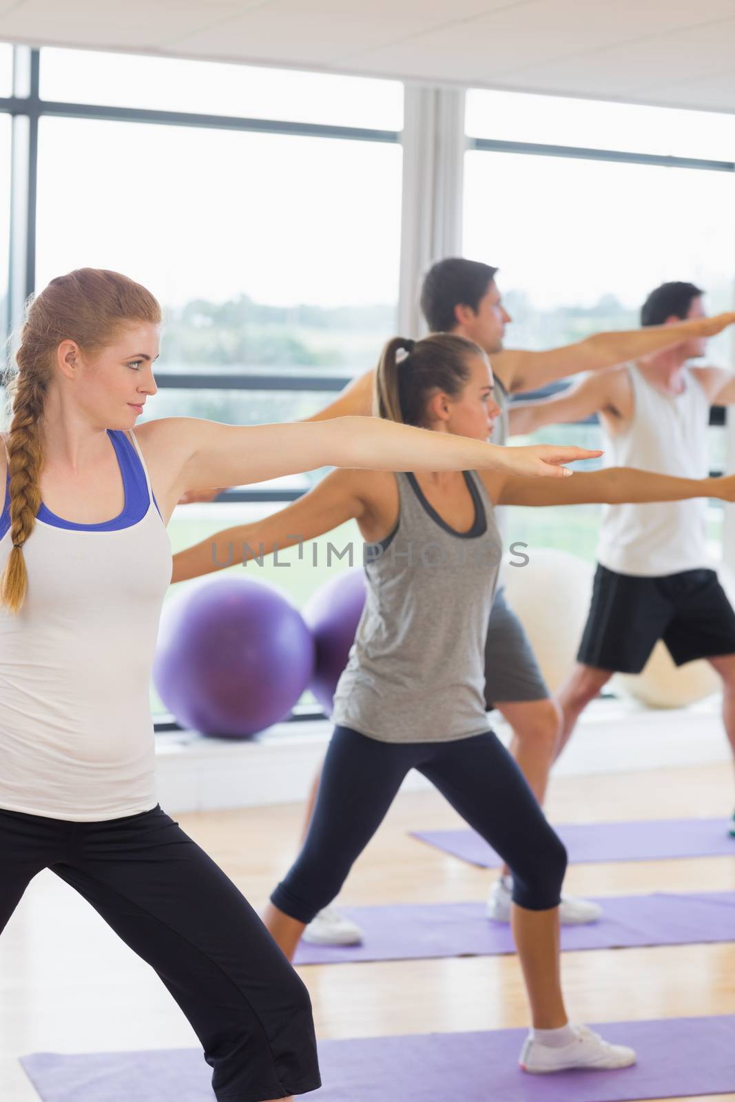 Sporty people stretching hands at yoga class in fitness studio by Wavebreakmedia