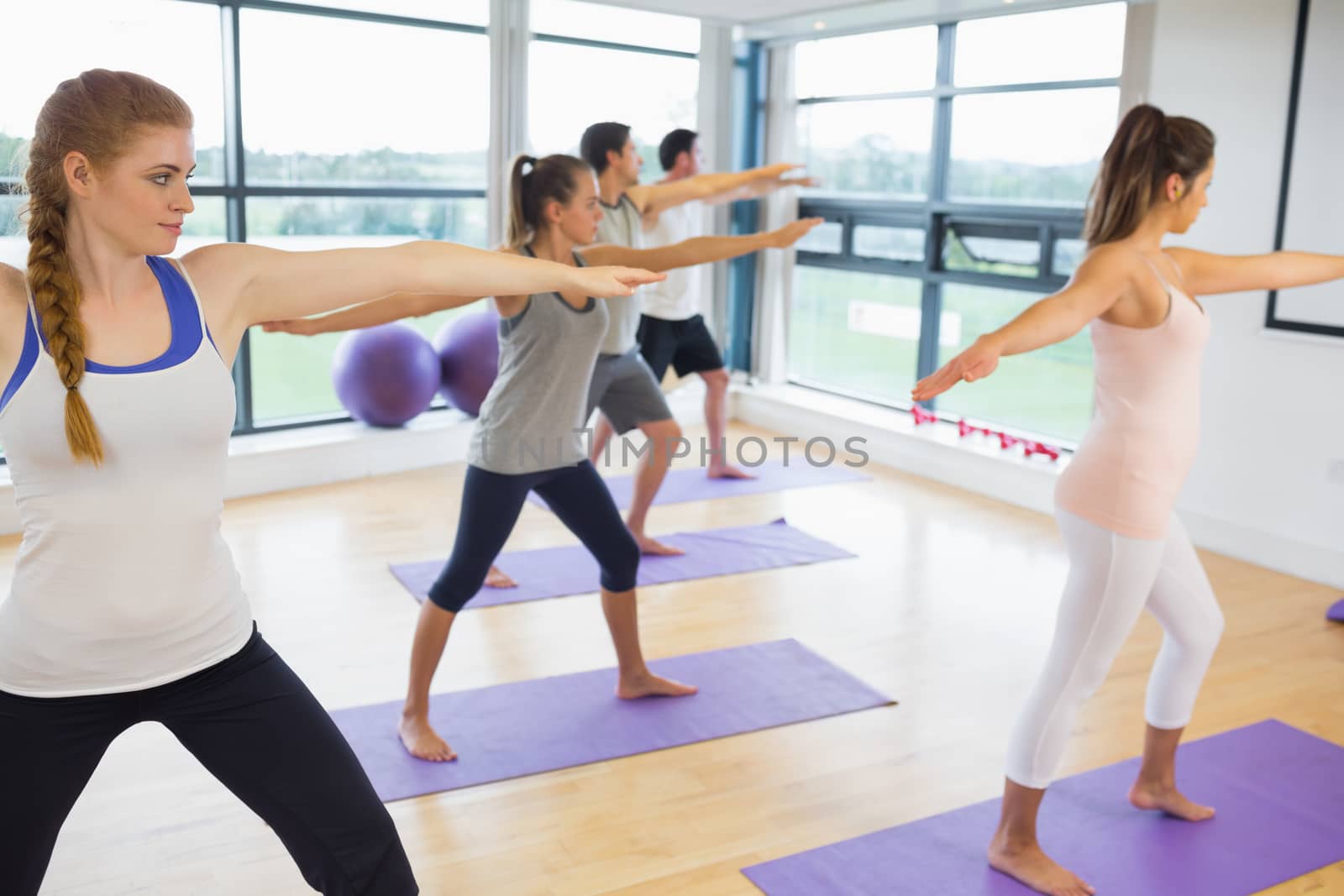 Full length of sporty people stretching hands at yoga class in fitness studio