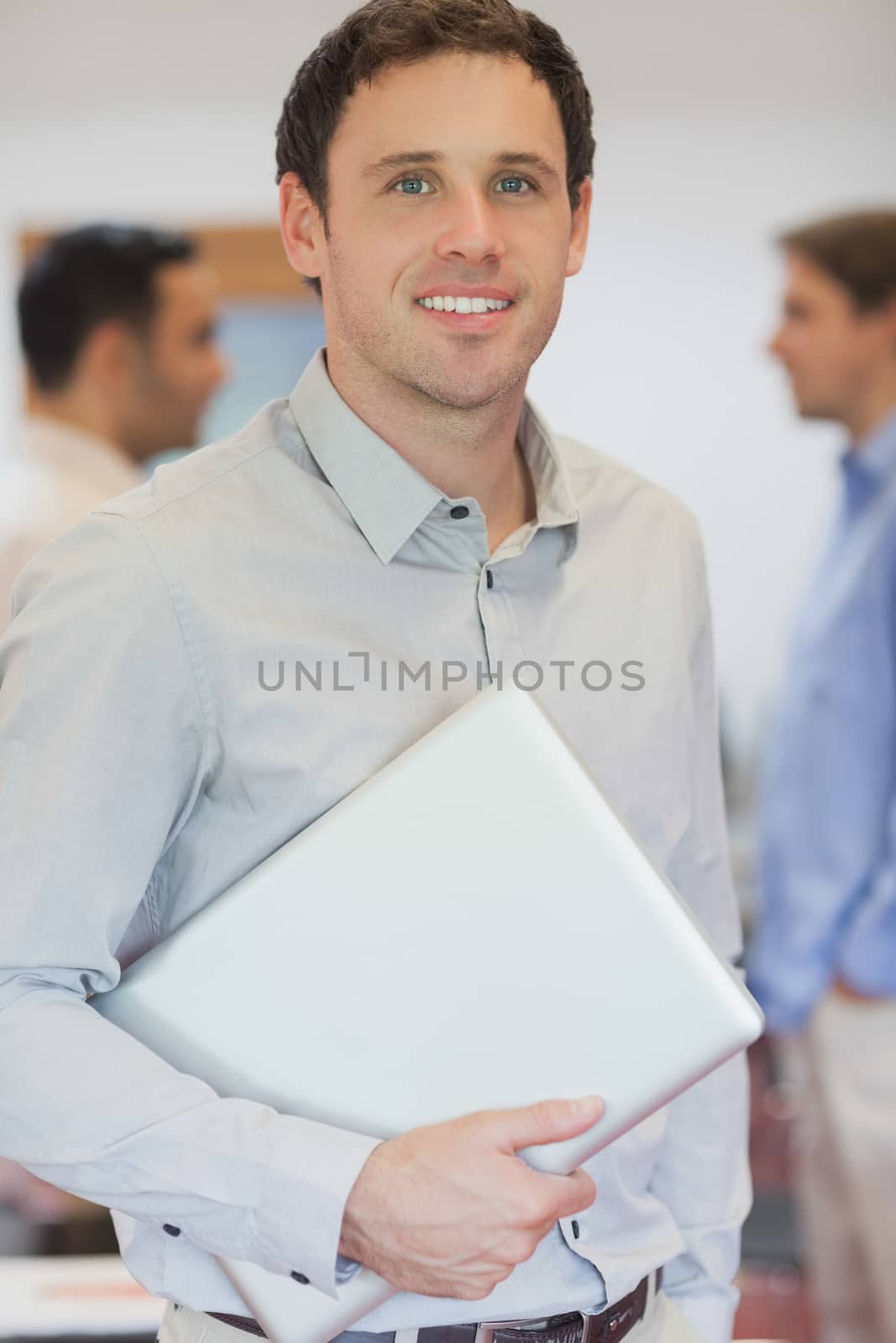 Attractive male mature student posing in classroom holding his laptop