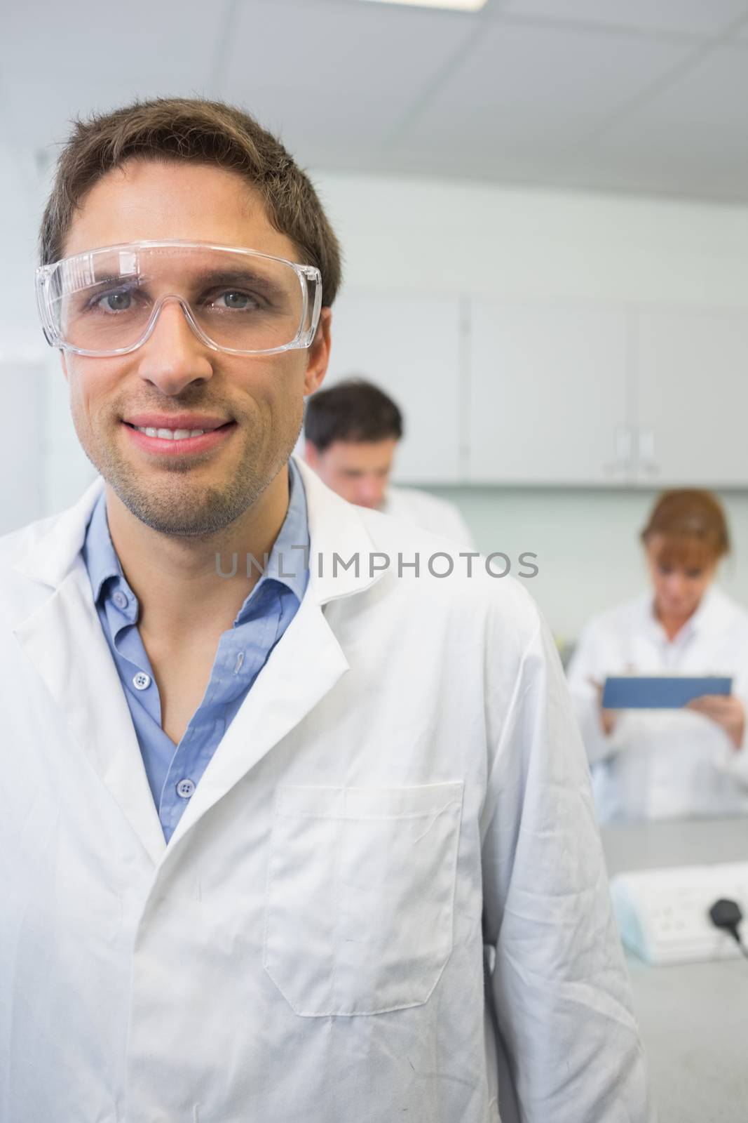 Portrait of a smiling scientist with colleagues at work in the laboratory