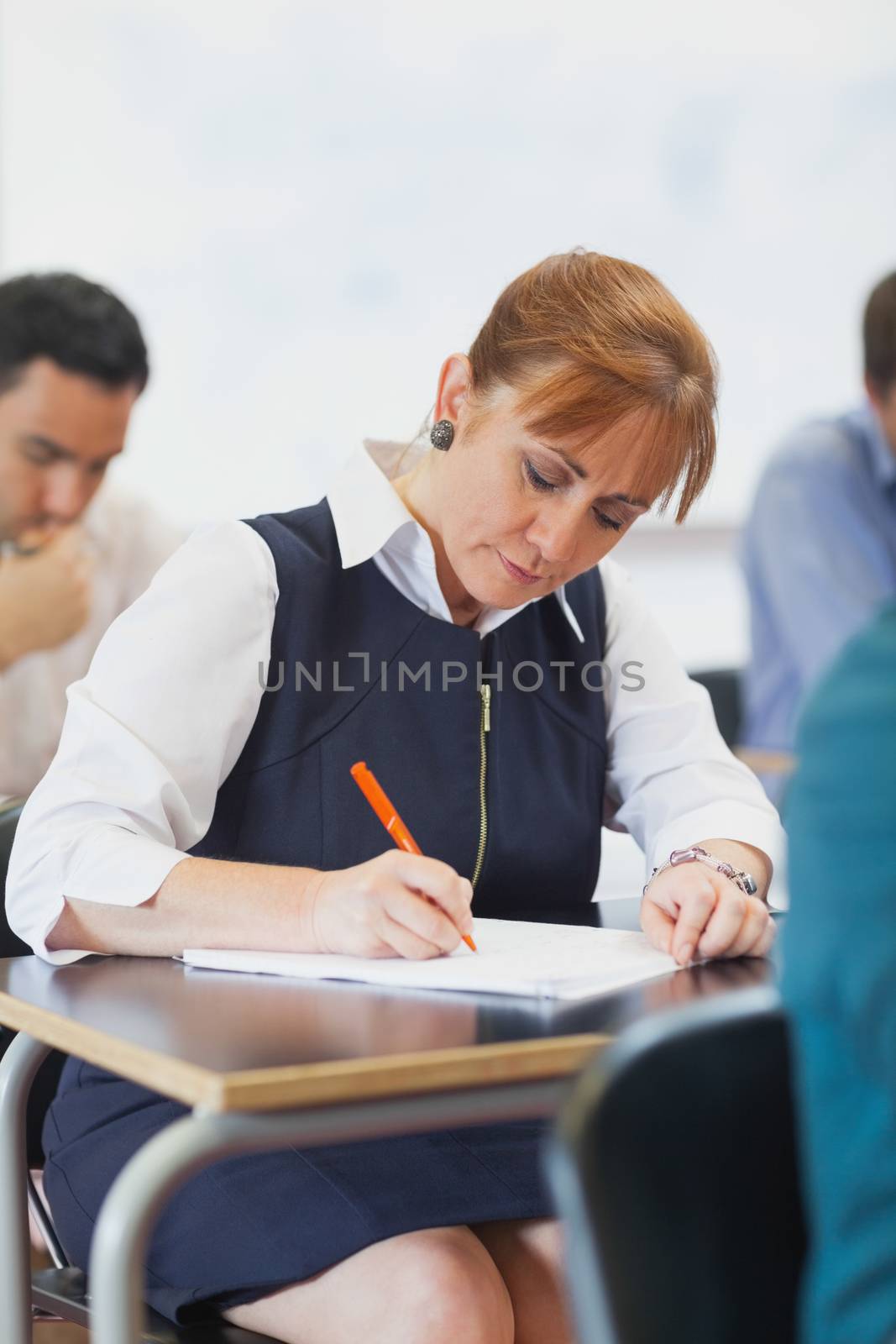 Concentrated female mature student sitting in classroom by Wavebreakmedia
