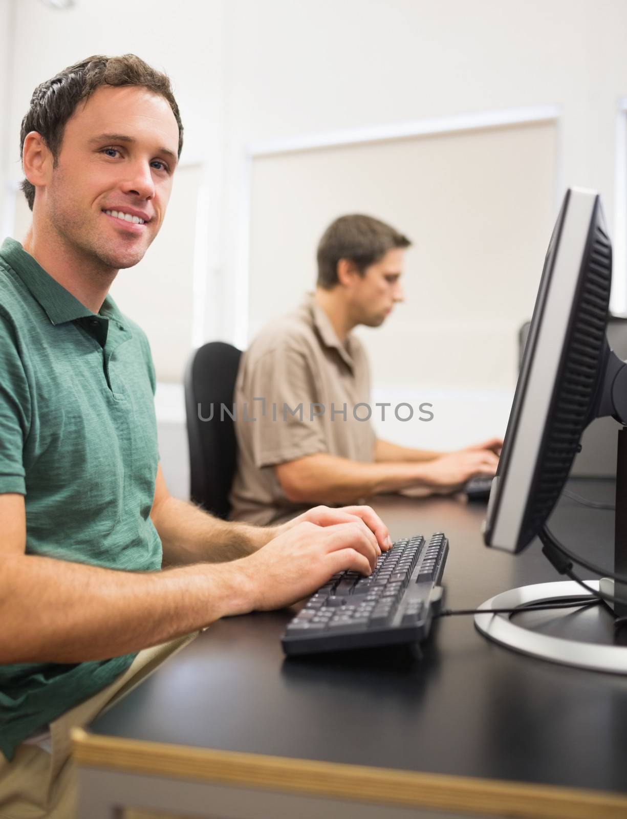 Portrait of a smiling man by other mature student using computers in the computer room