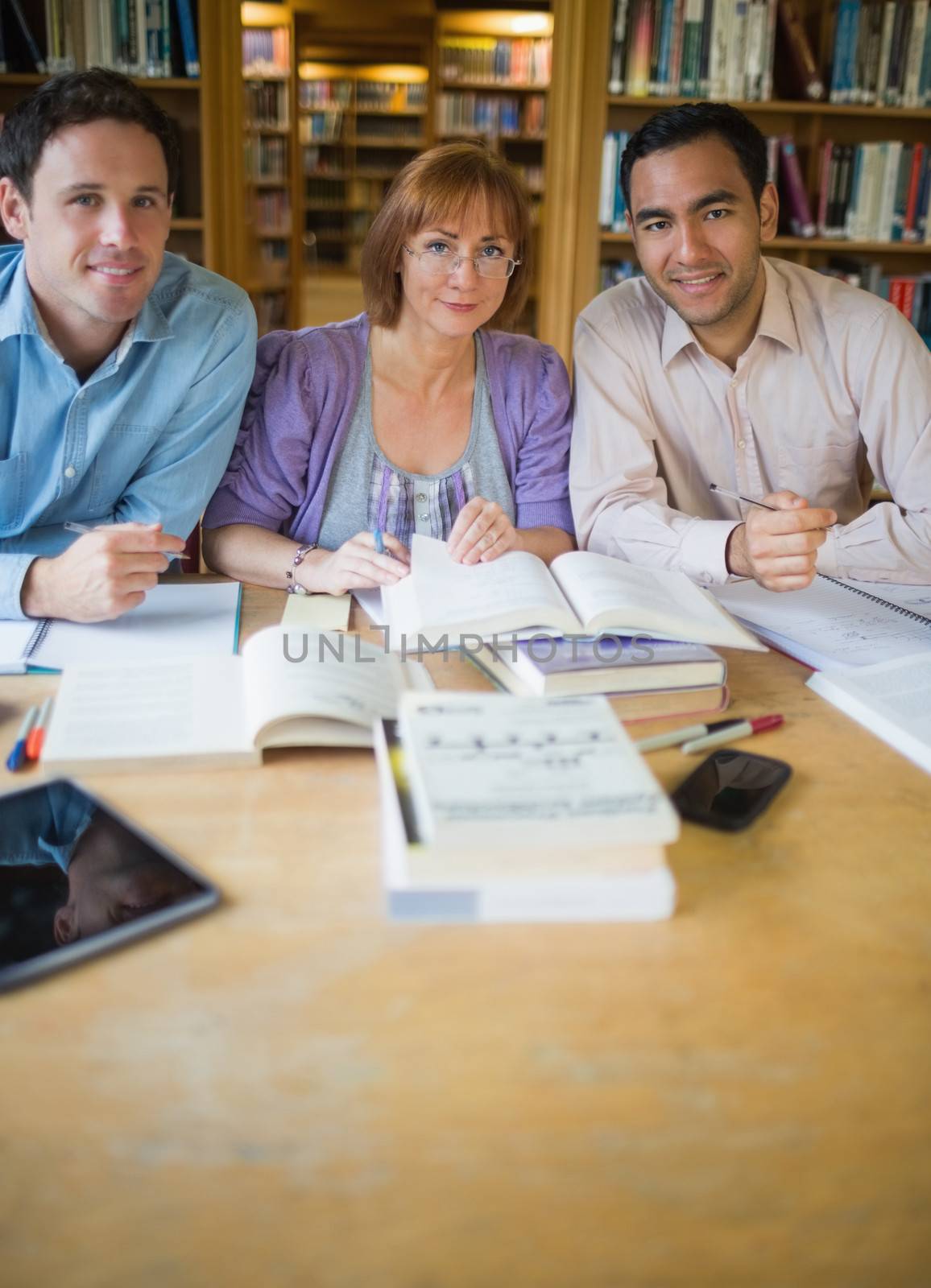 Portrait of three mature students studying together in the library