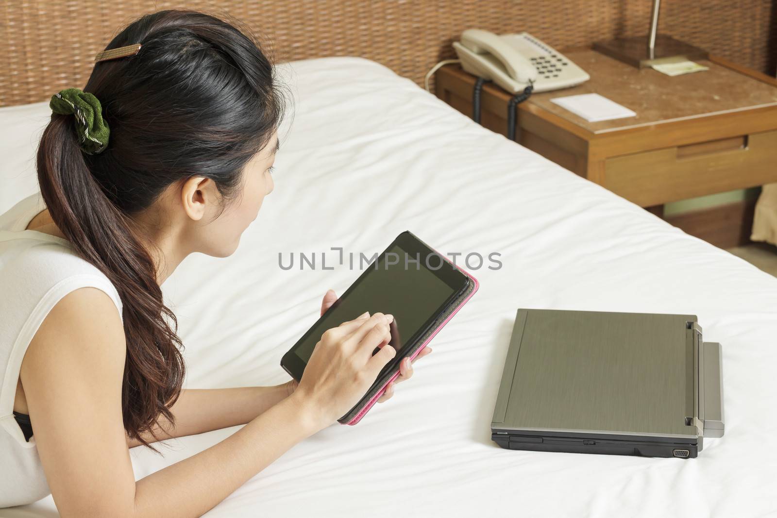 happy young asian woman working with tablet and notebook in bedr by FrameAngel