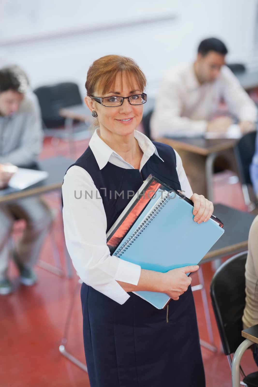 Pretty female teacher posing in her classroom holding some files by Wavebreakmedia