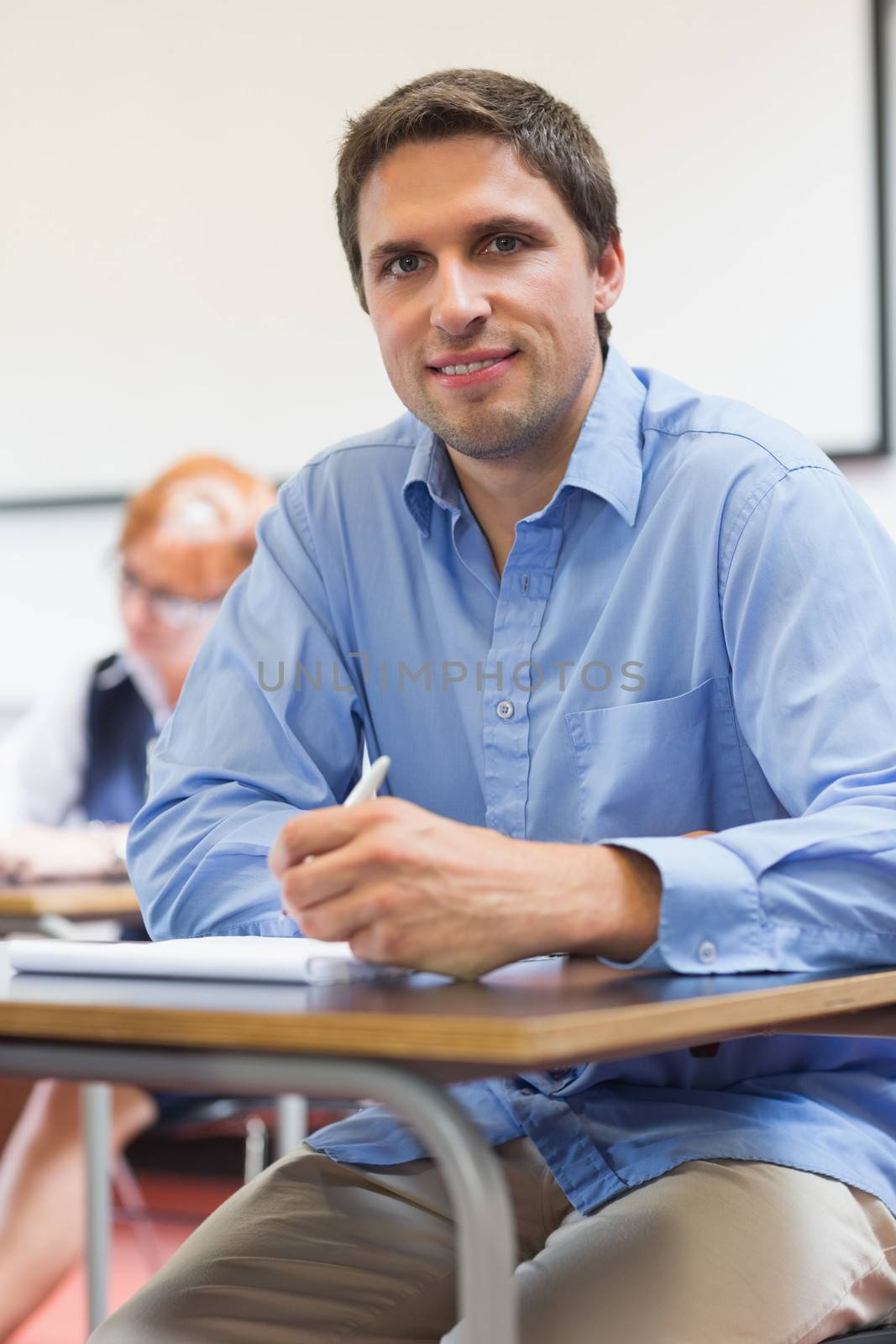 Portrait of a mature student taking notes with others in lecture in college