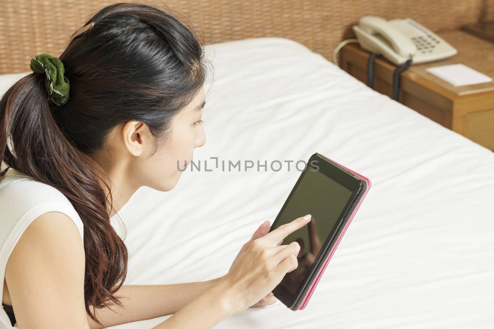 happy young asian woman working with tablet in bedroom by FrameAngel