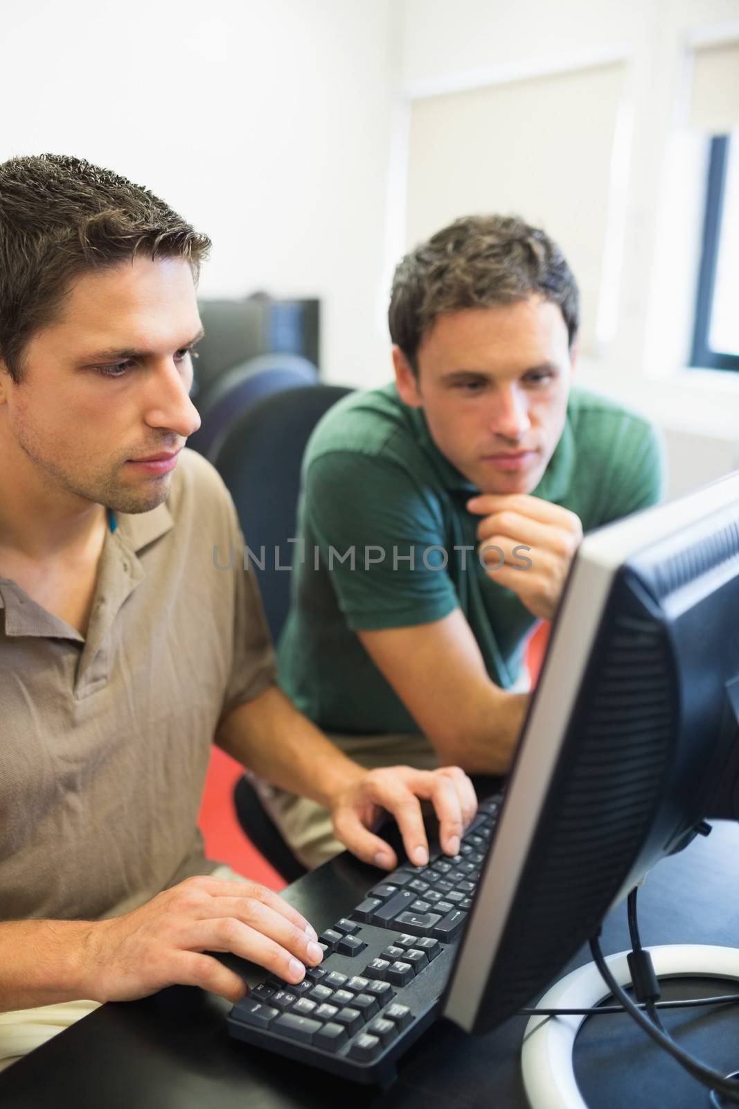 Concentrated teacher and mature student looking at computer screen in the computer room