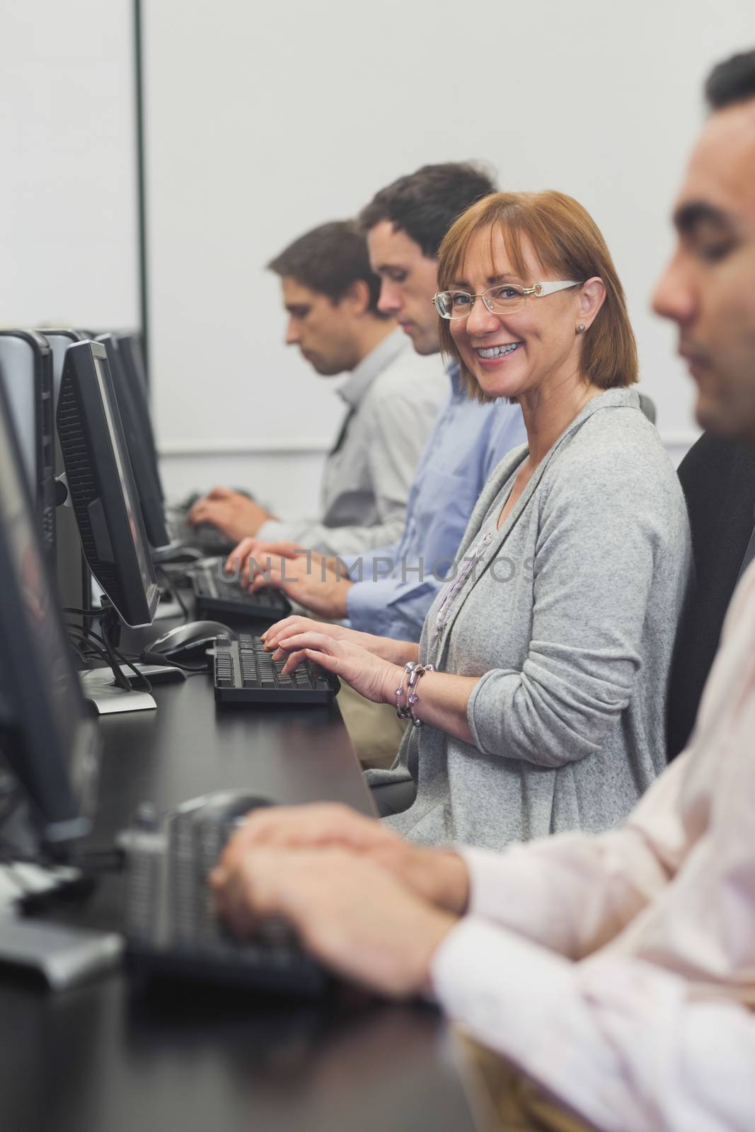 Female mature student sitting in computer class smiling at camera