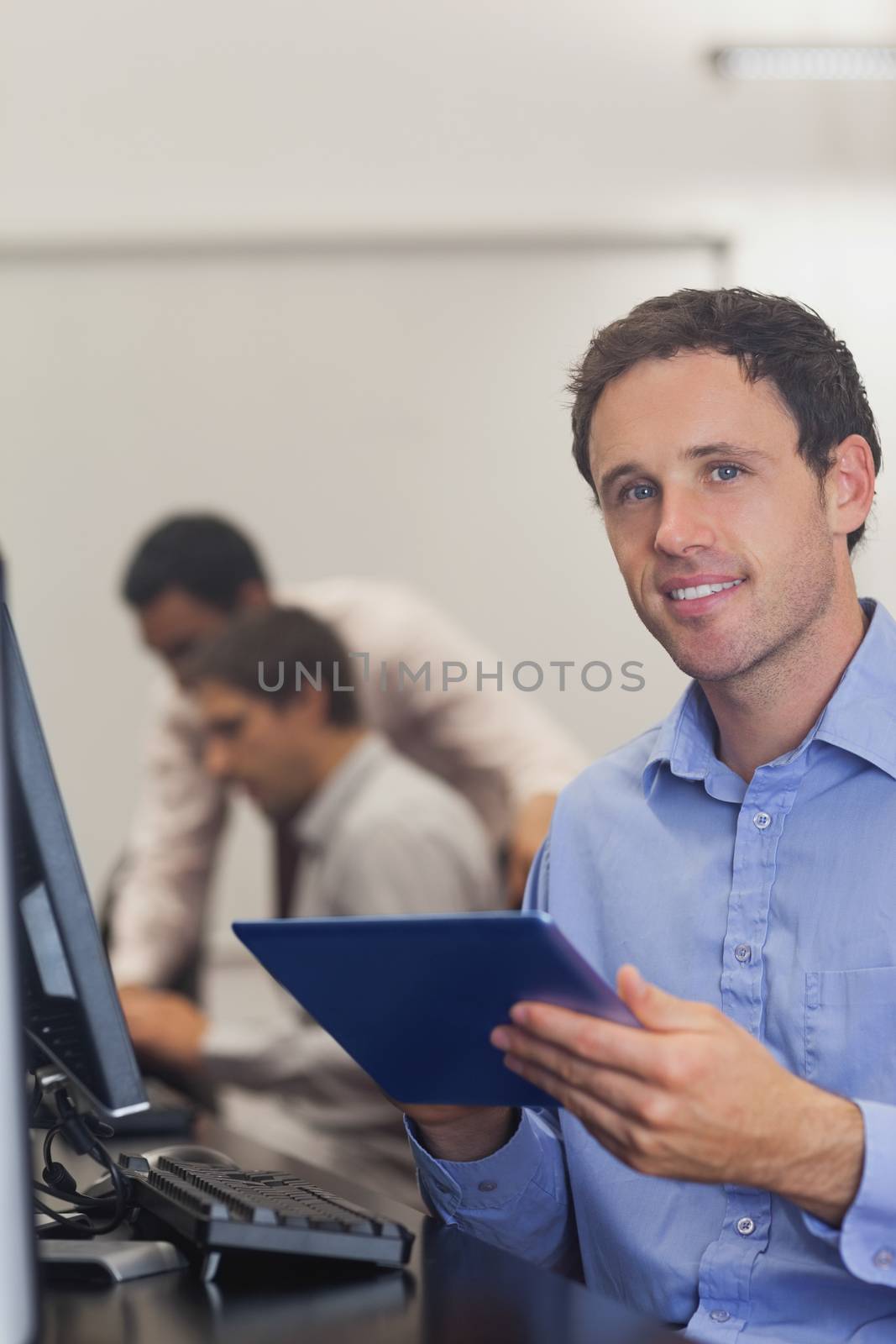 Content male student holding his tablet sitting in computer class by Wavebreakmedia