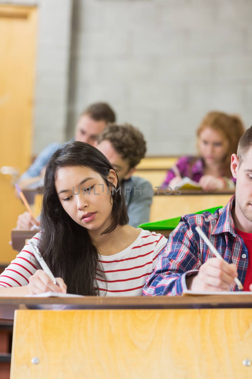 Group of young students writing notes in the classroom