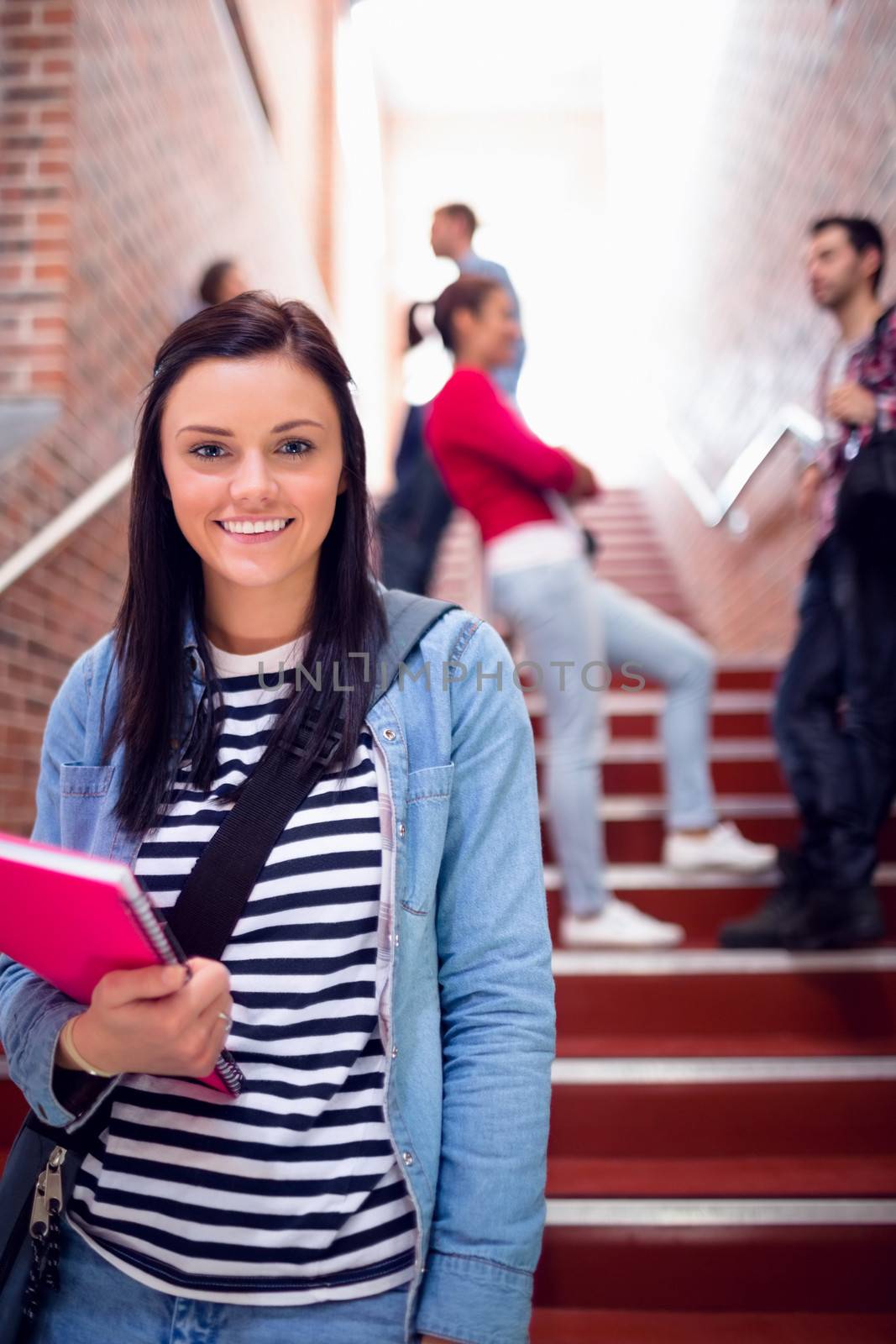 Female holding books with students on stairs in college by Wavebreakmedia