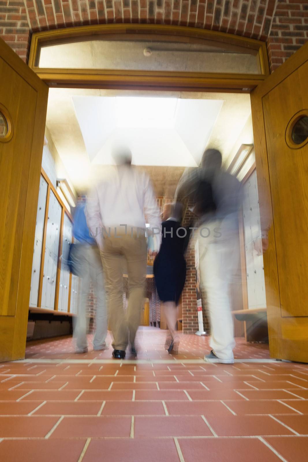 Rear view of a group of blurred people walking through open doors