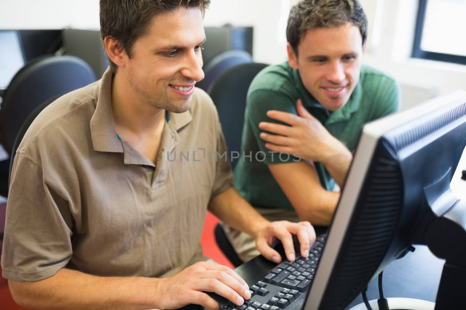 Smiling teacher and mature student using computer in the computer room