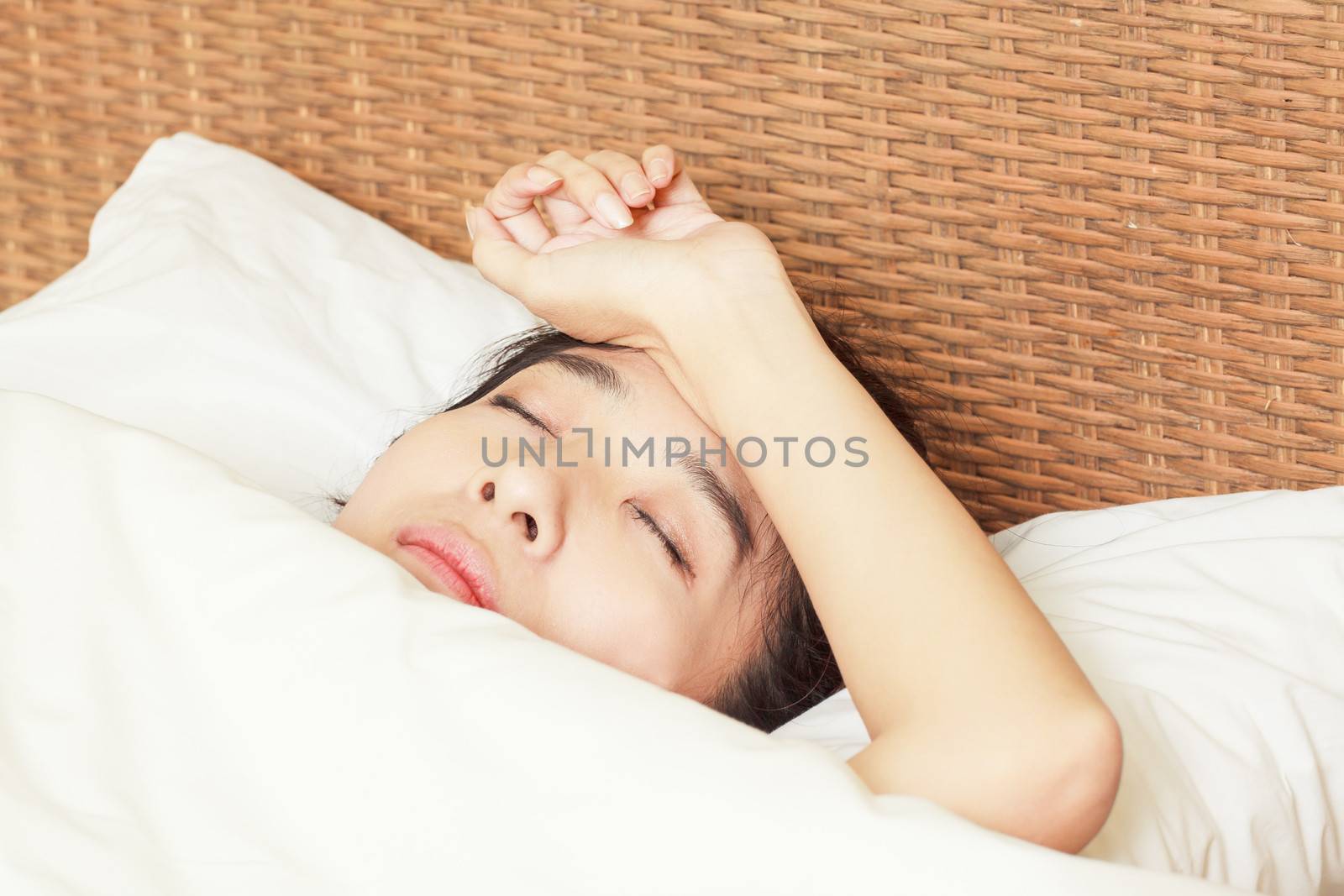 woman with headache lying on bed by FrameAngel