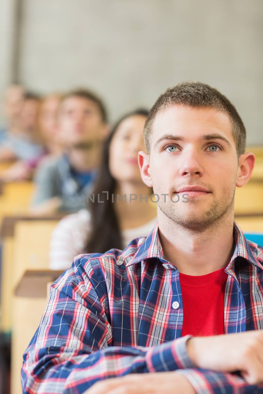 Close up of a young male student with others in a row at the college classroom
