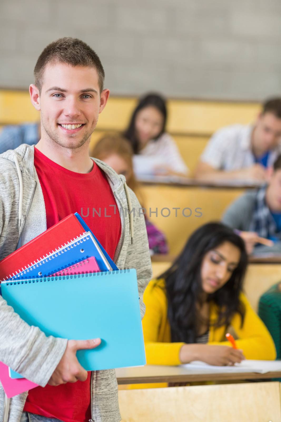 Smiling male with students sitting at lecture hall by Wavebreakmedia