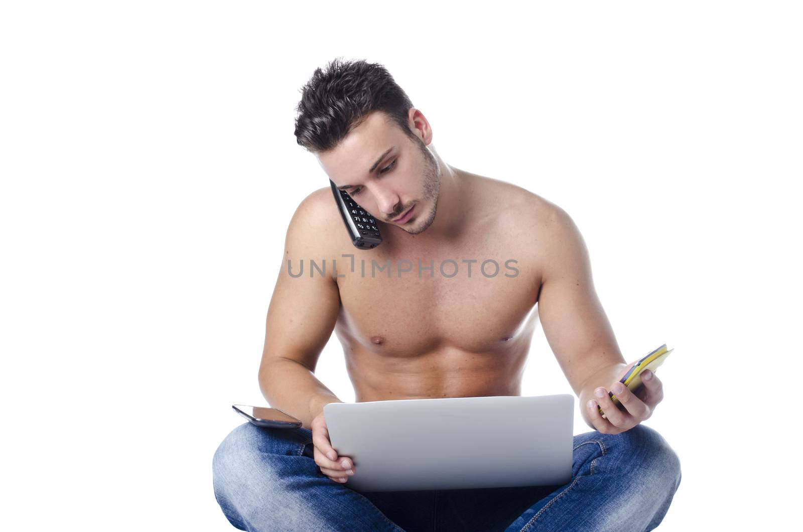 Shirtless muscular young man overwhelmed by technology, using laptop computer, PC tablet, phones