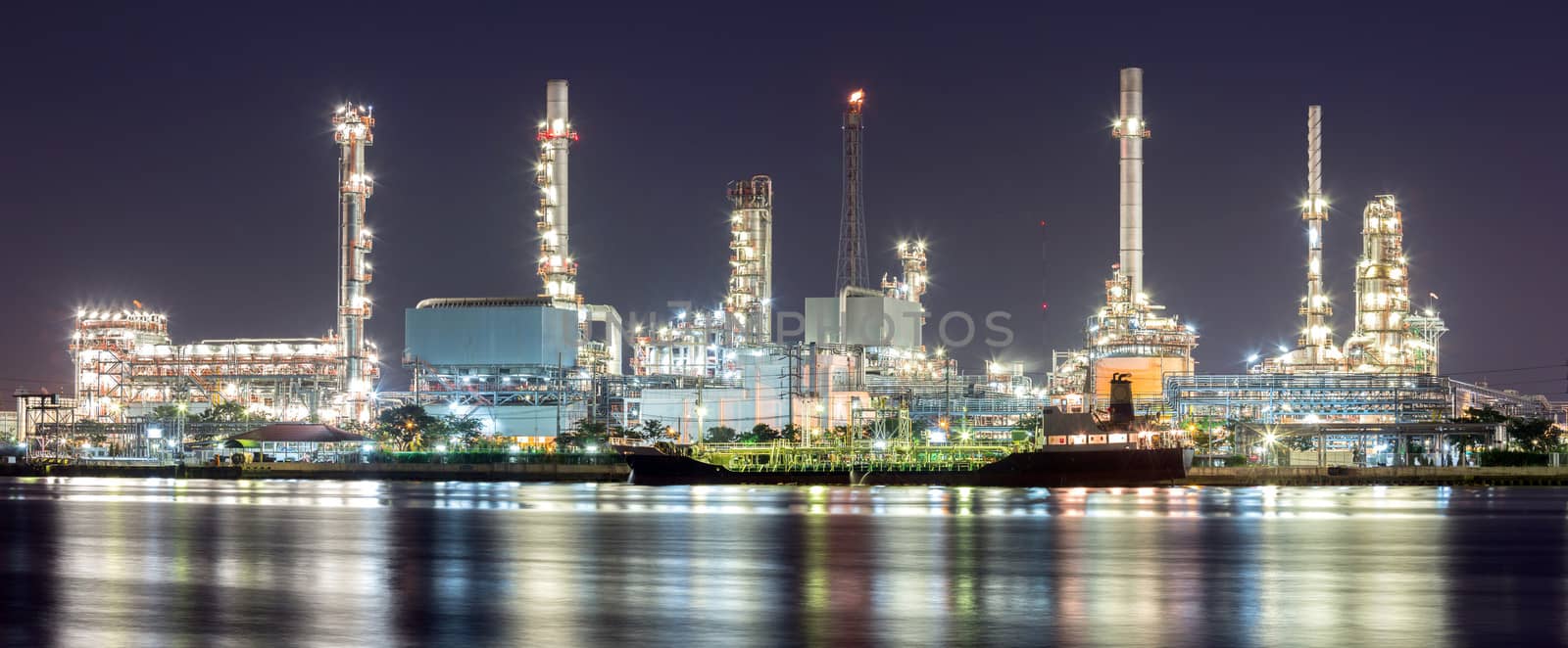 Panorama landscape of Oil refinery plant along river with tanker at night