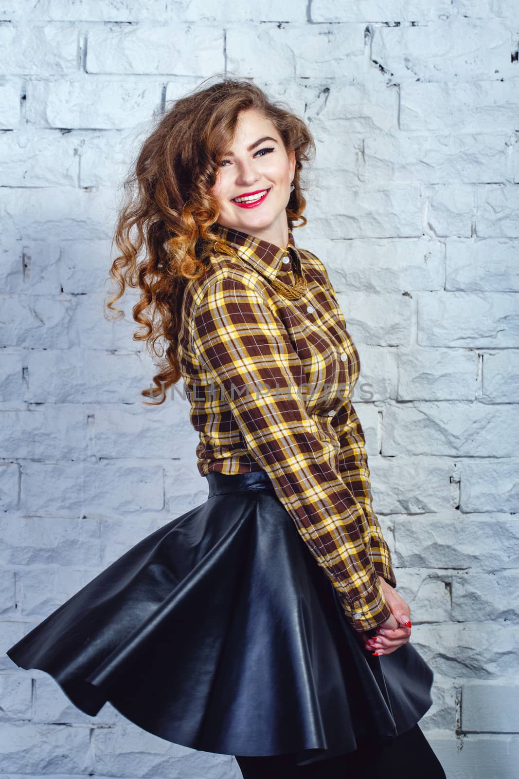 Attractive young girl in plaid shirt and leather skirt