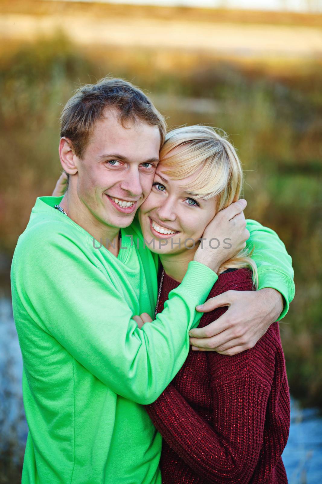 Young couple tenderly and lovingly embrace each other on banks of river