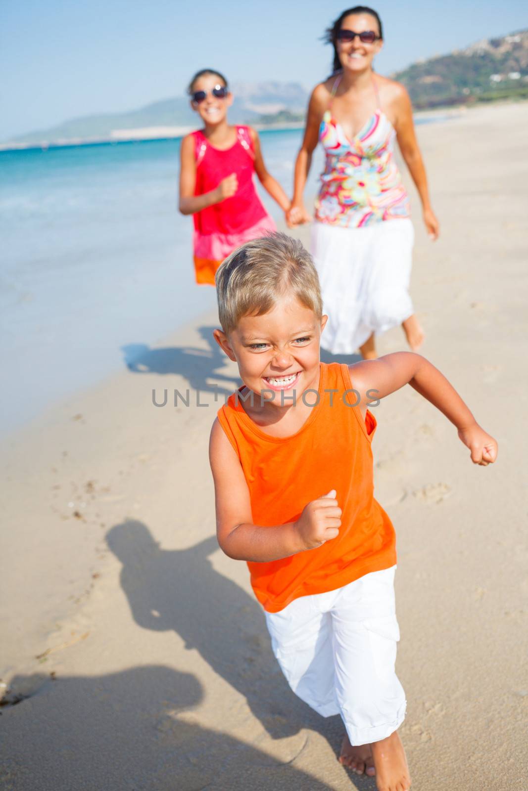 Cute boy with sister and mother on the beach by maxoliki