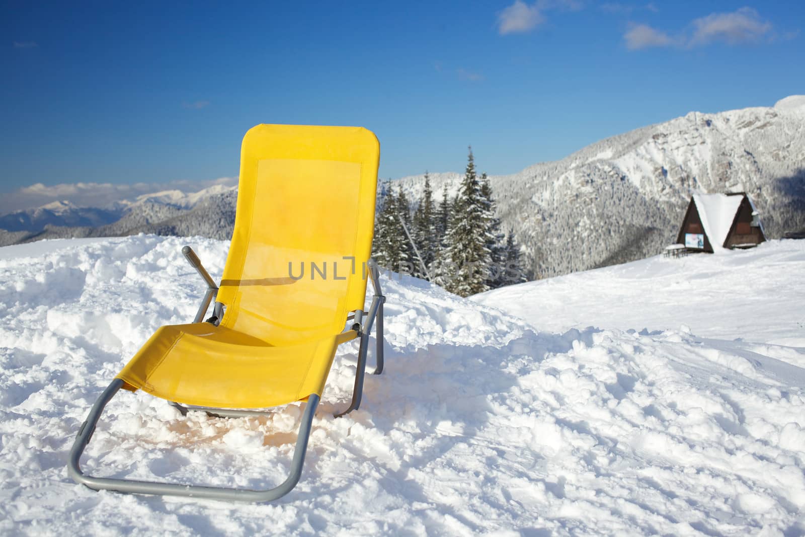 Concept of relax. Chair on top of mountain range at winter season sunny day with blue sky in background.