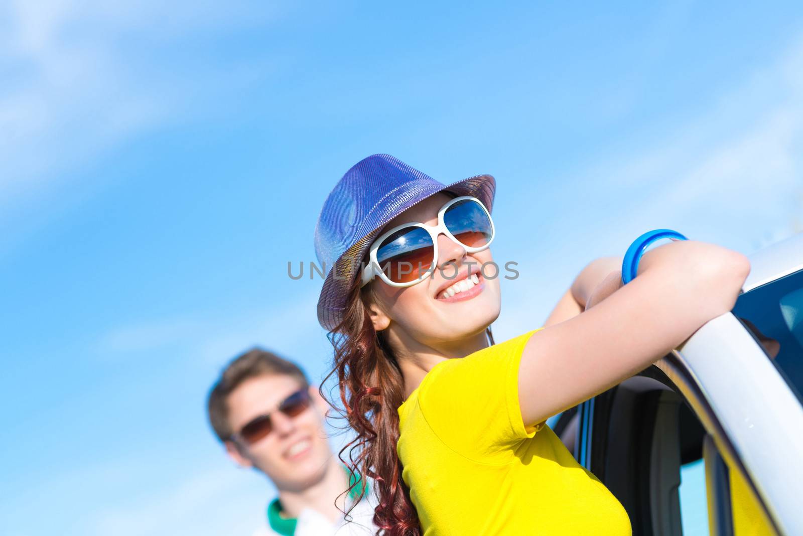 young attractive woman in sunglasses and hat stands next to a car, a close-up portrait