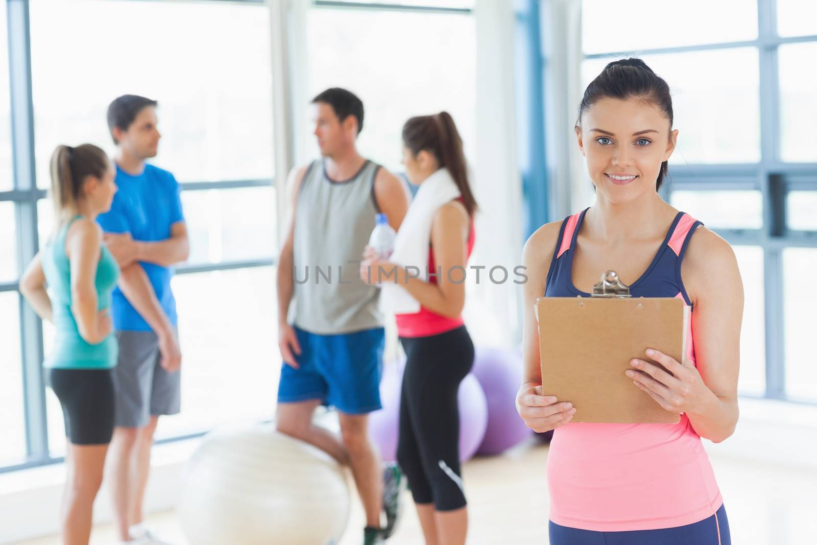 Portrait of an instructor with fitness class in background in fitness studio