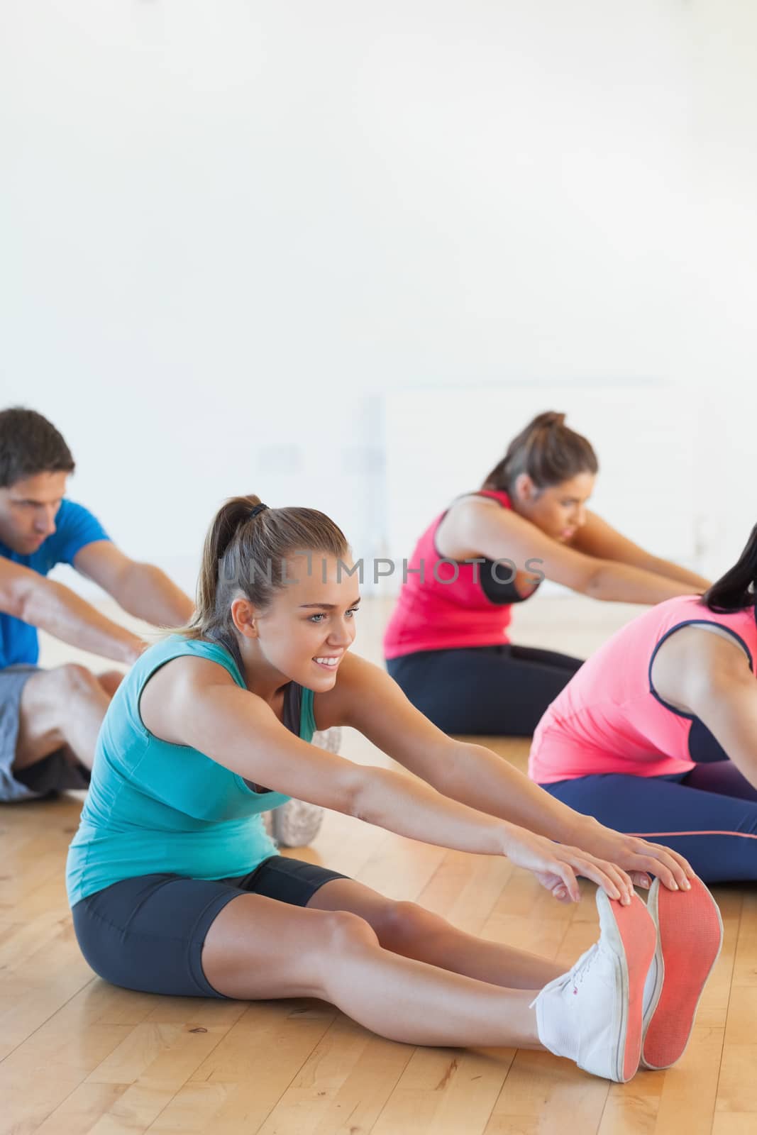 Class and instructor stretching legs in exercise room by Wavebreakmedia