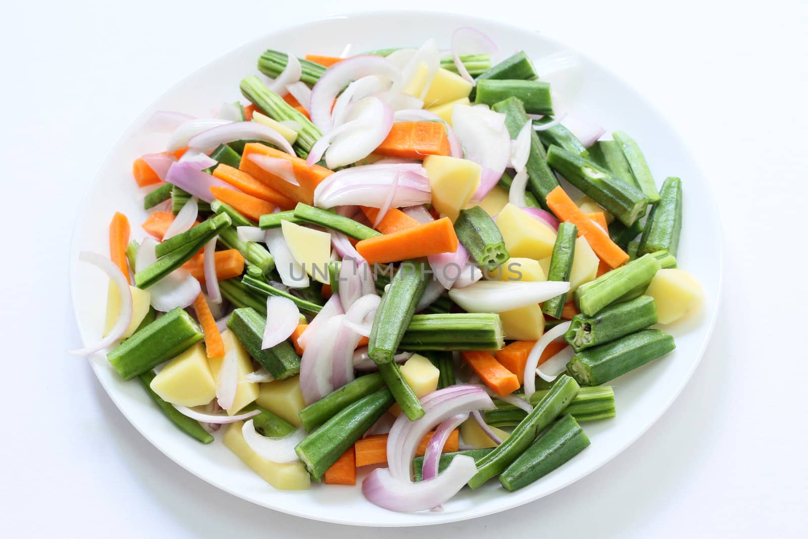 Fresh mixed vegetables chopped and placed in a plate with white background