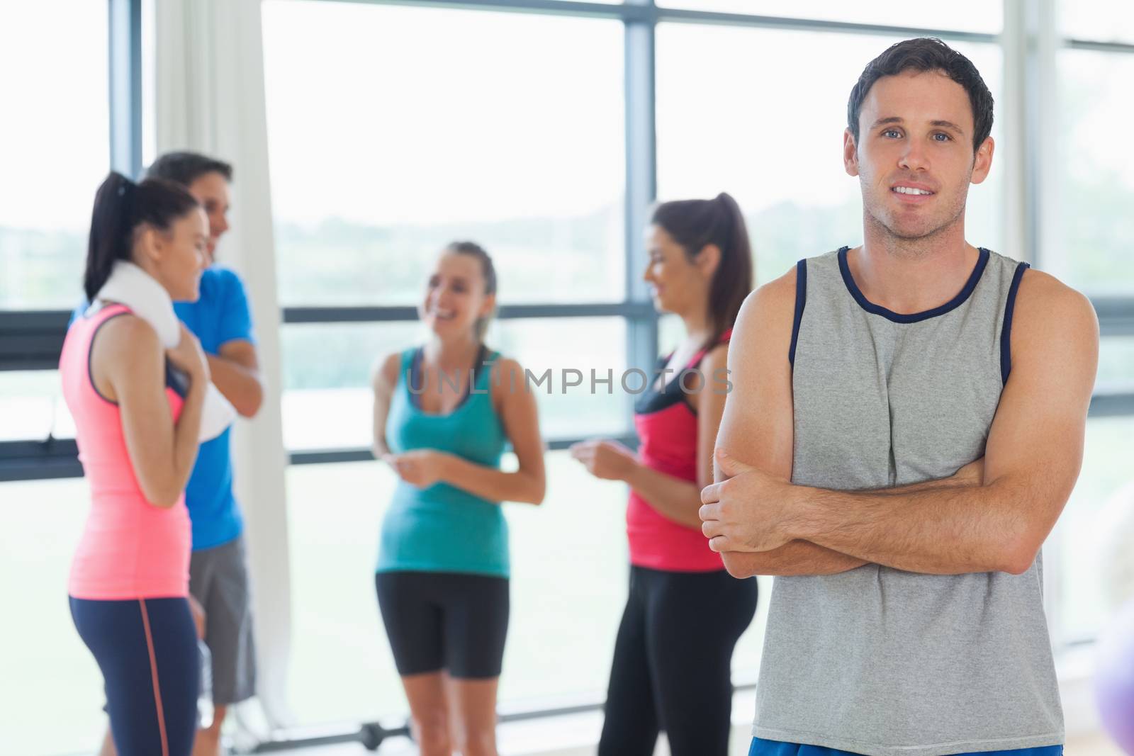 Portrait of an instructor with fitness class in background in fitness studio