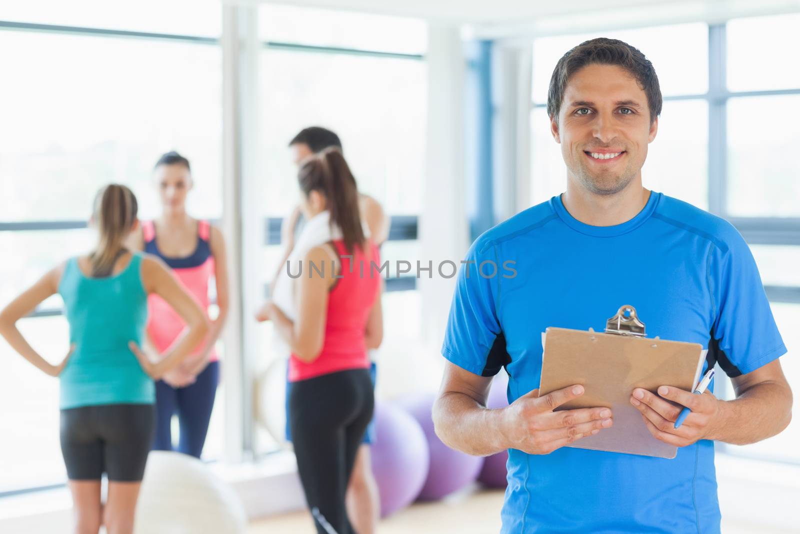 Portrait of an instructor with fitness class in background in fitness studio