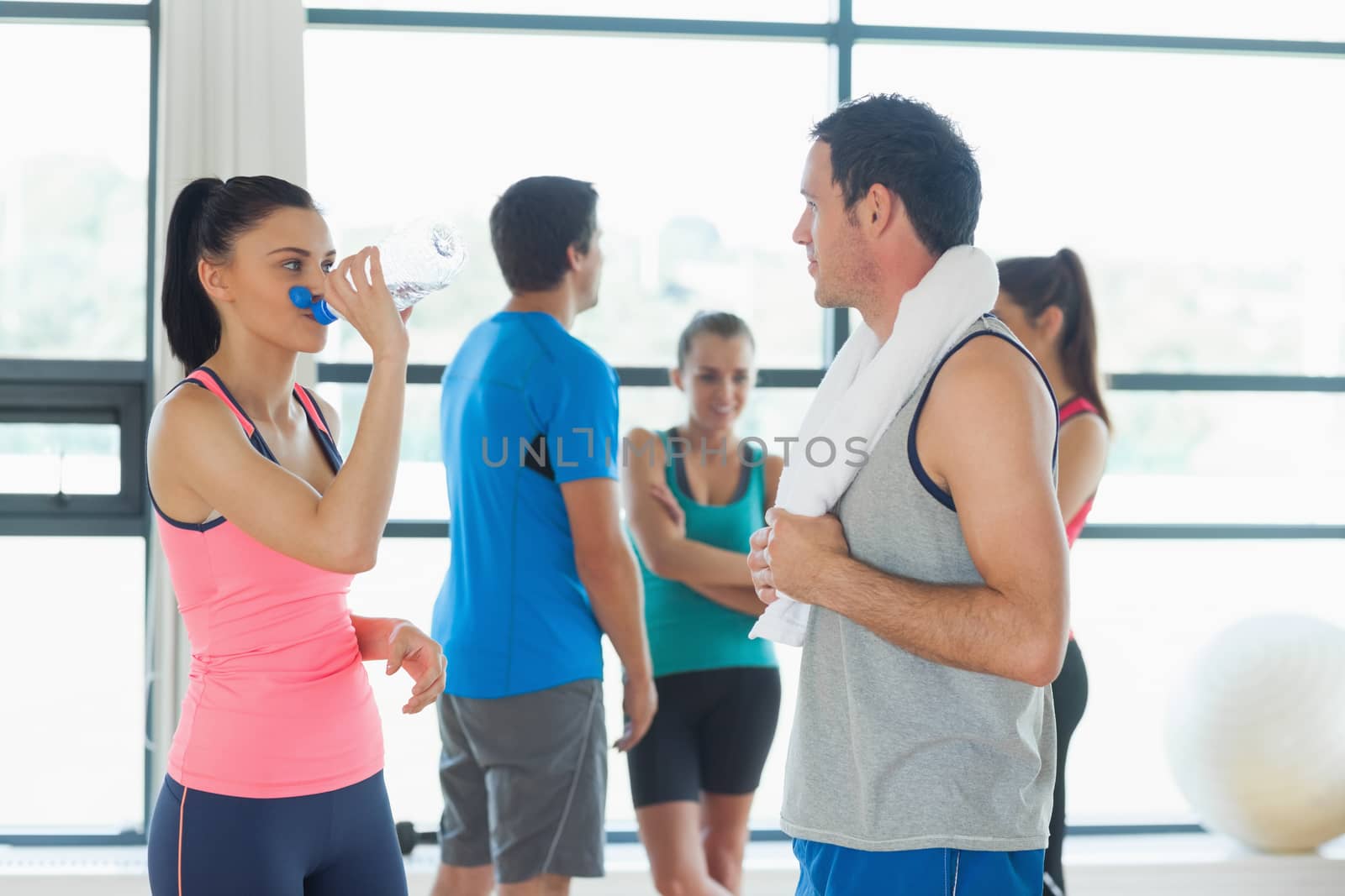 Fit couple with friends standing in background in bright exercise room