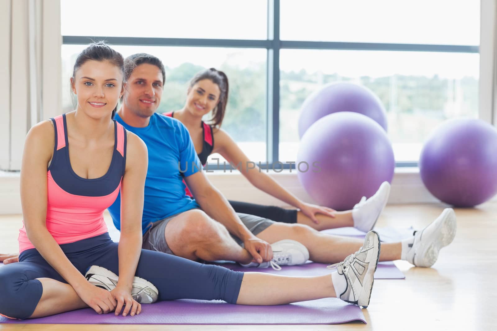 Fitness class and instructor sitting on exercise mats by Wavebreakmedia