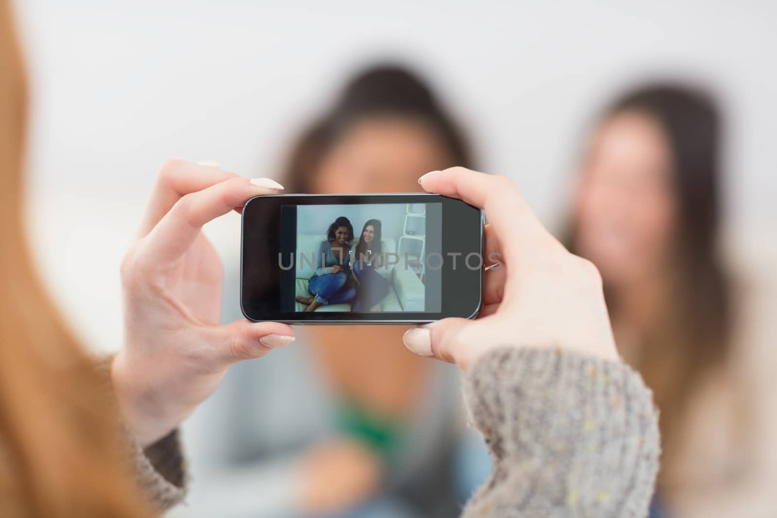 Close up of a woman photographing friends with smartphone by Wavebreakmedia