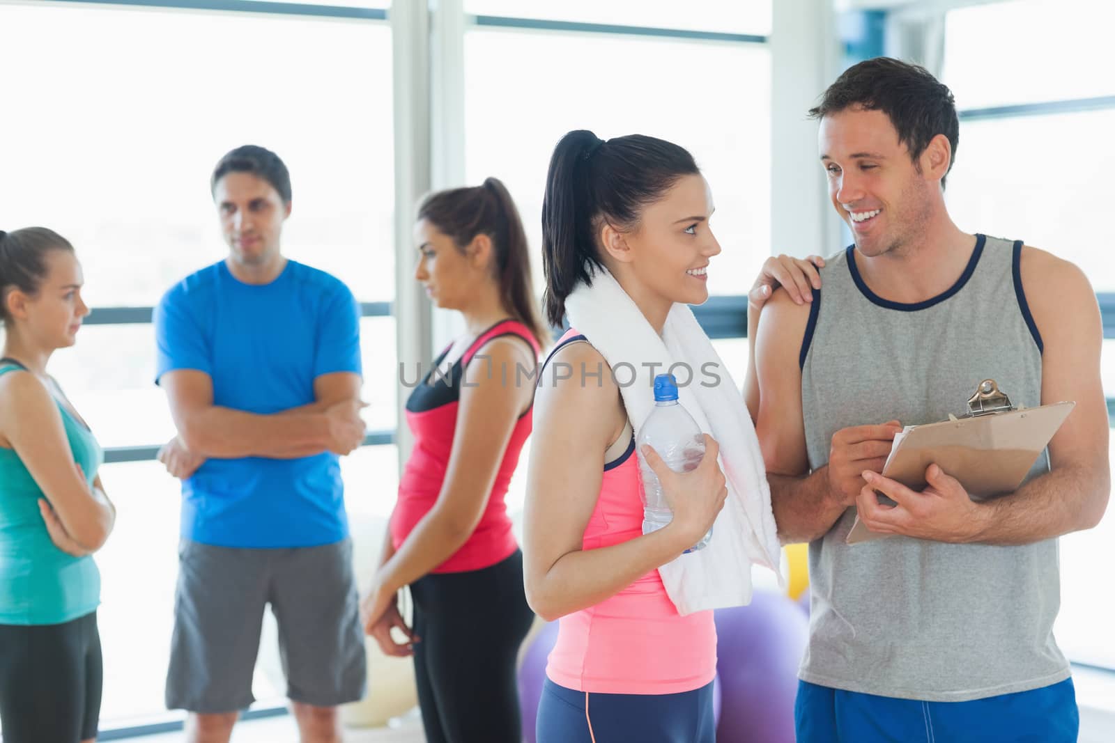 Fit couple with friends standing in background in bright exercise room