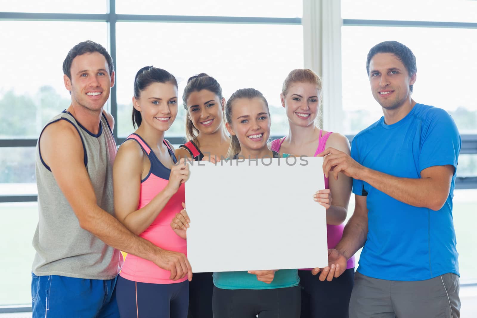 Portrait of a group of fitness class holding blank paper by Wavebreakmedia